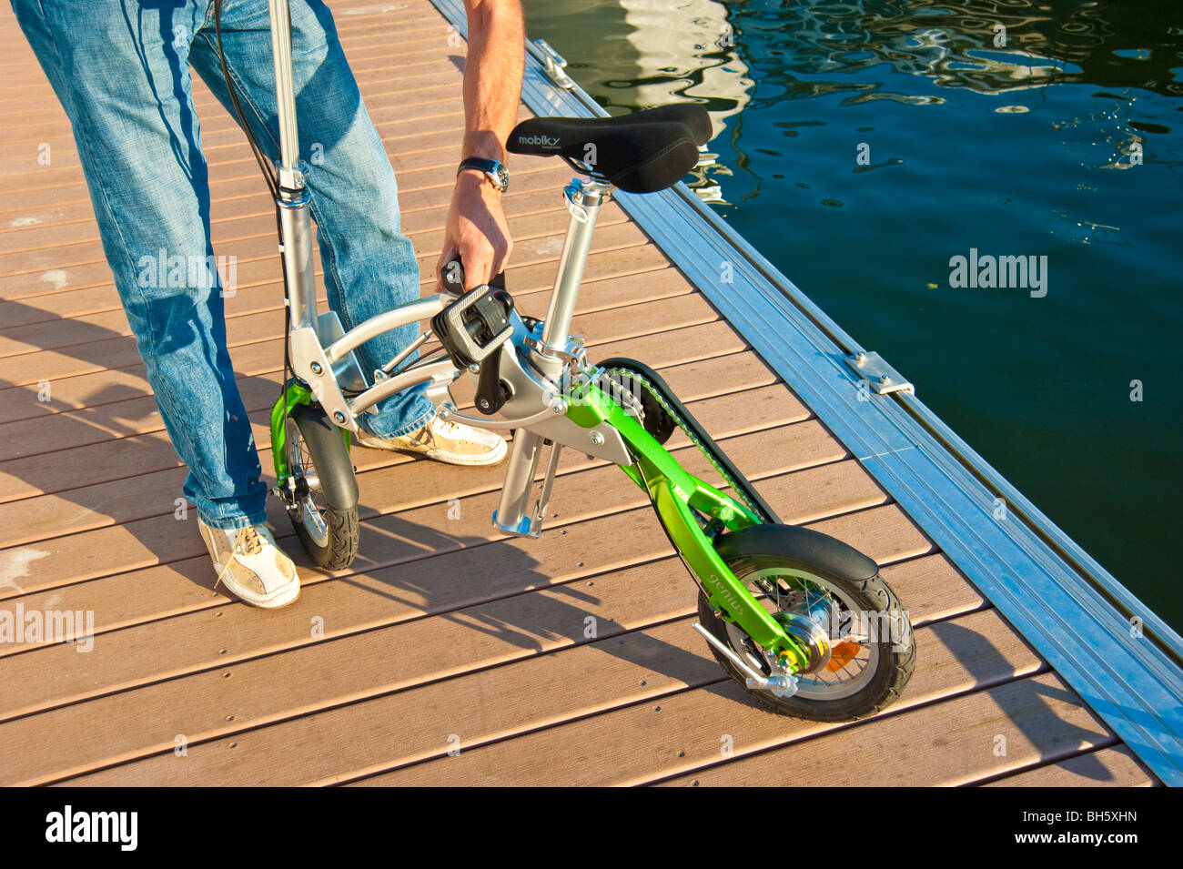 L'homme dépliant une Mobiky vélo sur un débarcadère avec yachts Photo Stock  - Alamy