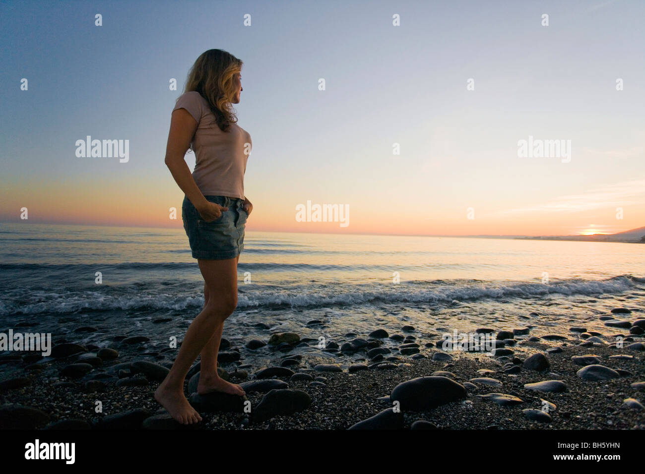 Femme sur plage en regardant le coucher du soleil low angle Banque D'Images