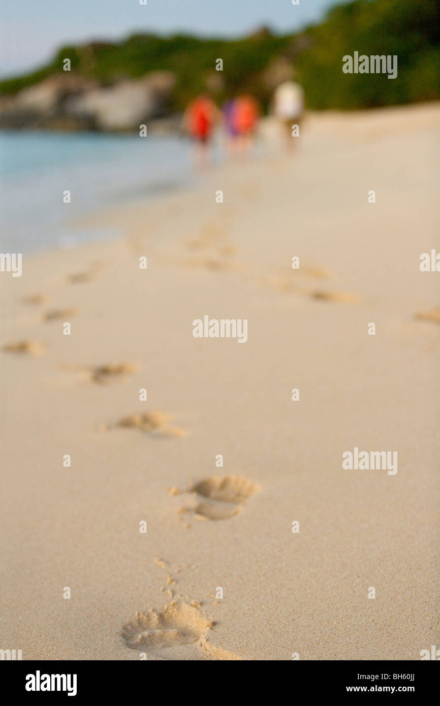 Empreintes de pas sur une plage tropicale des Caraïbes et des touristes dans l'arrière-plan. Banque D'Images
