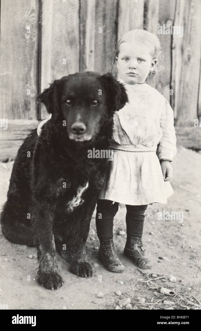 Petite fille gardée par grand chien noir Banque D'Images