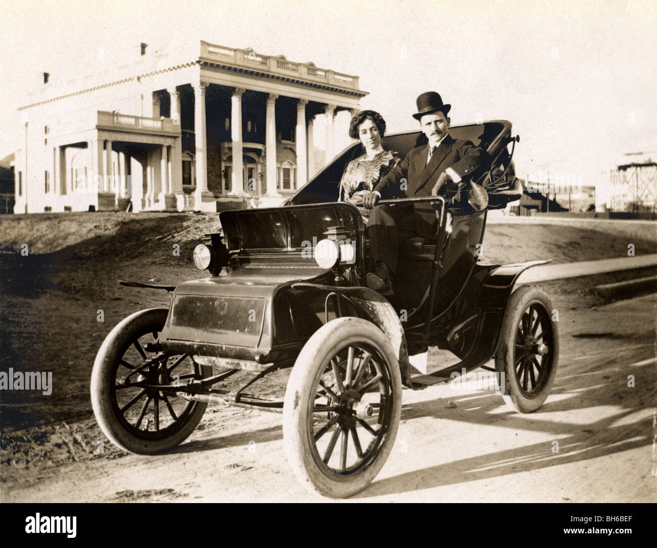 Couple au volant la voiture électrique en face de Mansion Banque D'Images