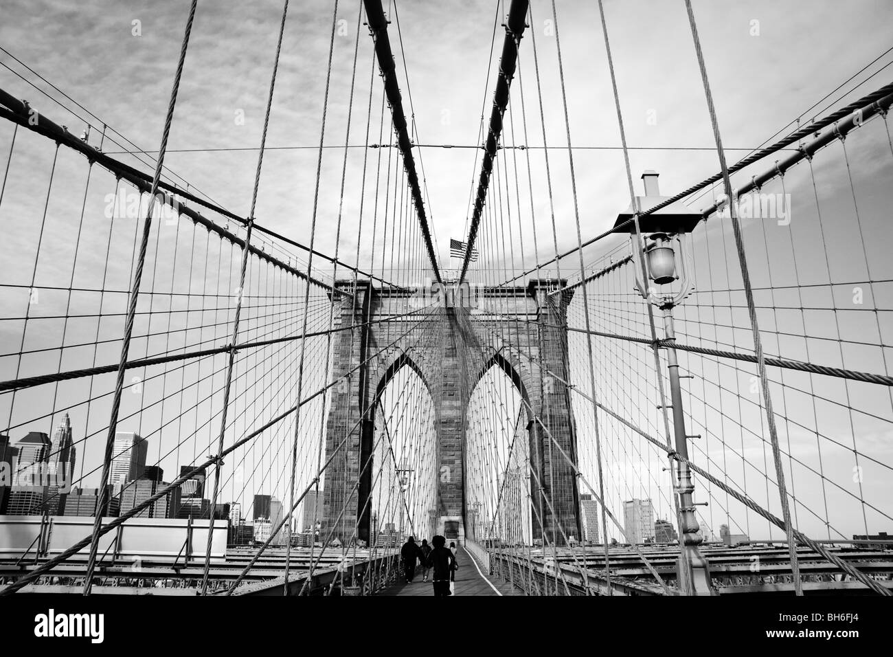 Une vue monochrome d'une tour et des câbles de suspension sur le pont de Brooklyn à New York. Le drapeau américain est visible sur la tour Banque D'Images