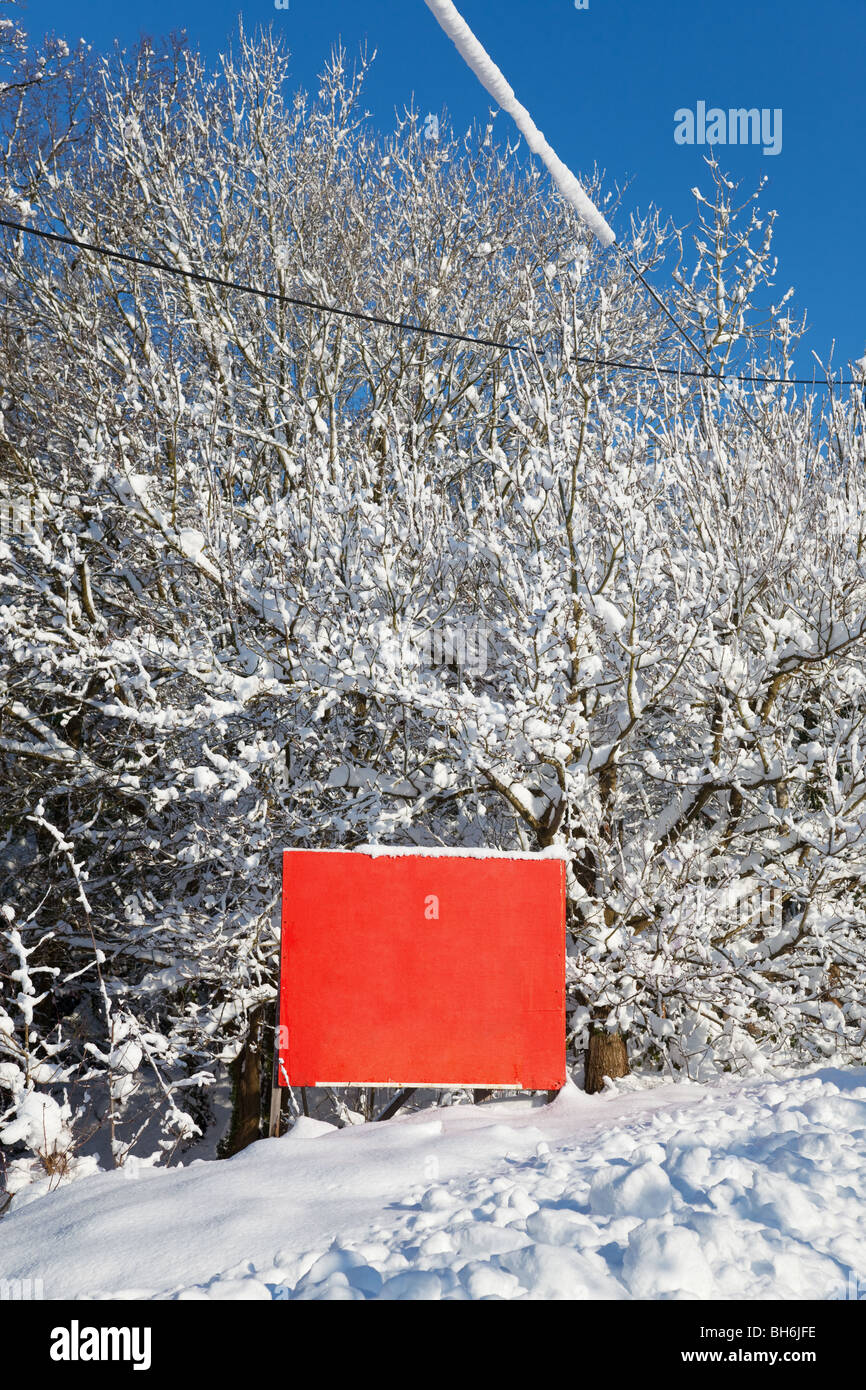 Un blank red old weathered wooden sign dans la neige, ajouter votre propre message. Banque D'Images
