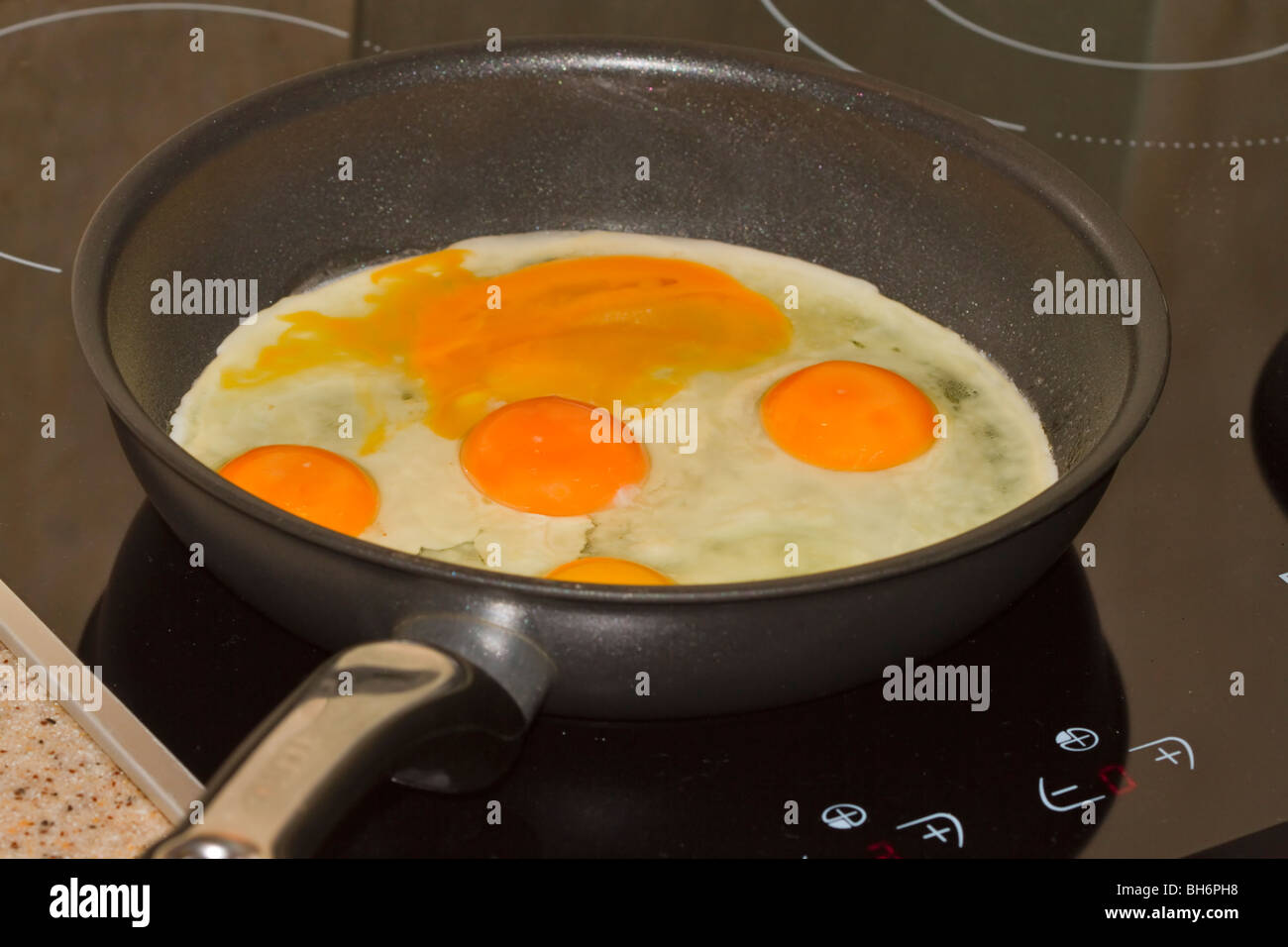 Oeufs dans le poêlon. Cinq oeufs frais dans une poêle. Un oeuf est cassé. Banque D'Images