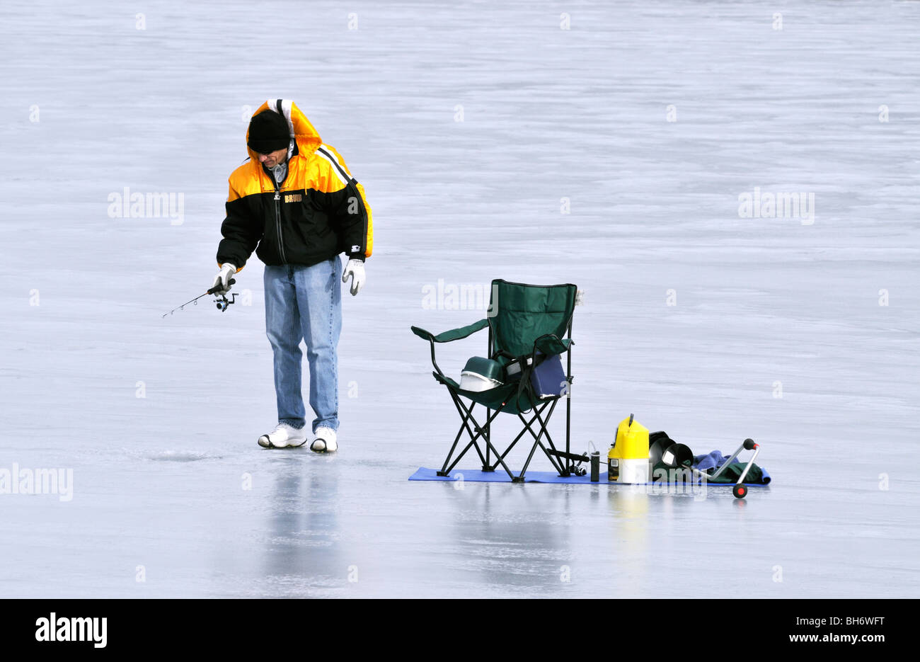 Homme seul la pêche blanche sur lac gelé avec chaise et engins à Cape Cod USA Banque D'Images