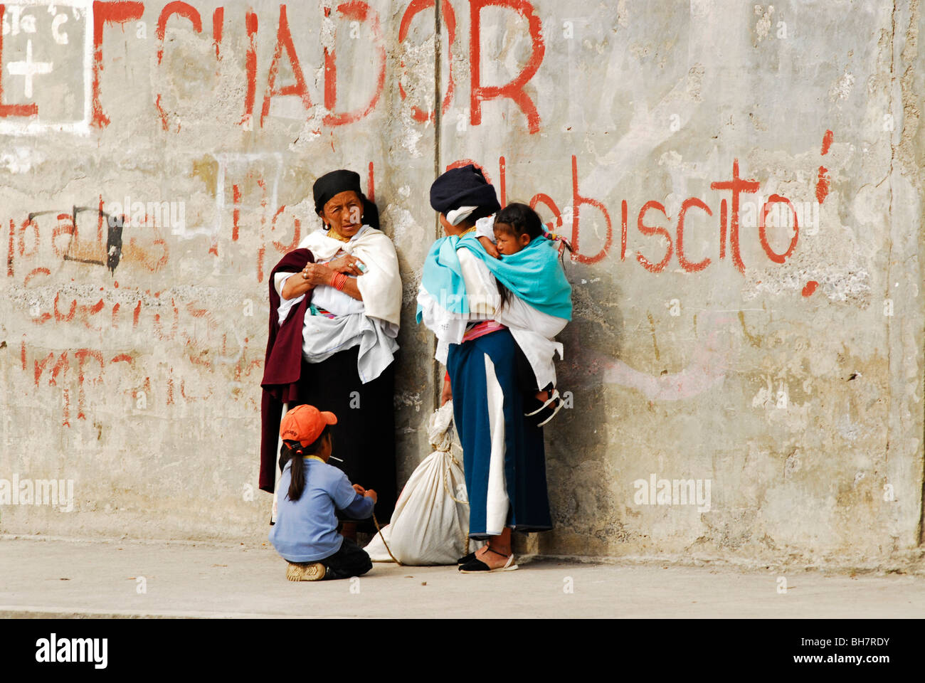 L'Équateur, Otavalo, voir des femmes autochtones portant des vêtements traditionnels et de longues jupes debout contre un vieux mur délabré avec Banque D'Images