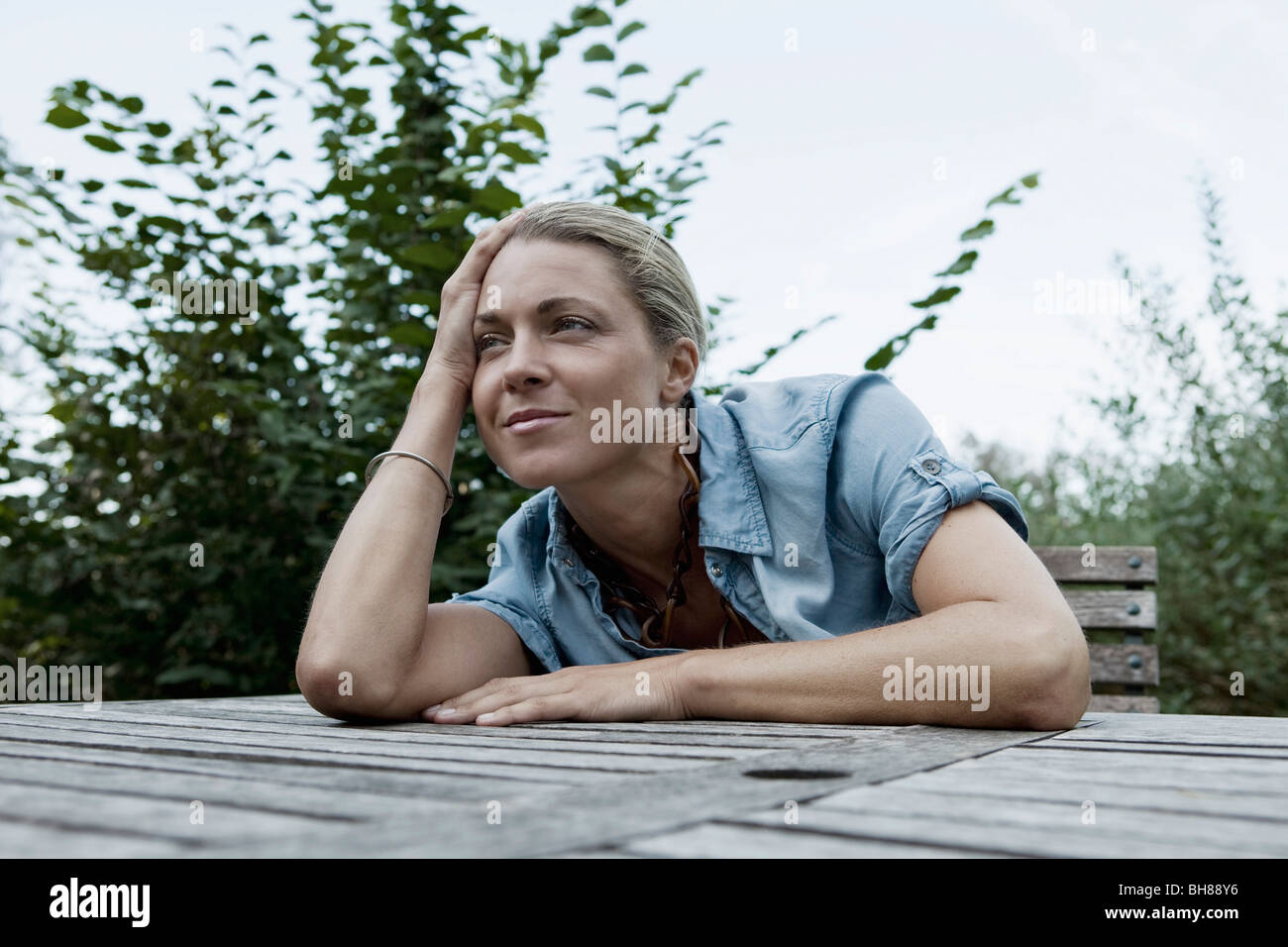 Une femme assise à une table en plein air, scène non urbaines Banque D'Images
