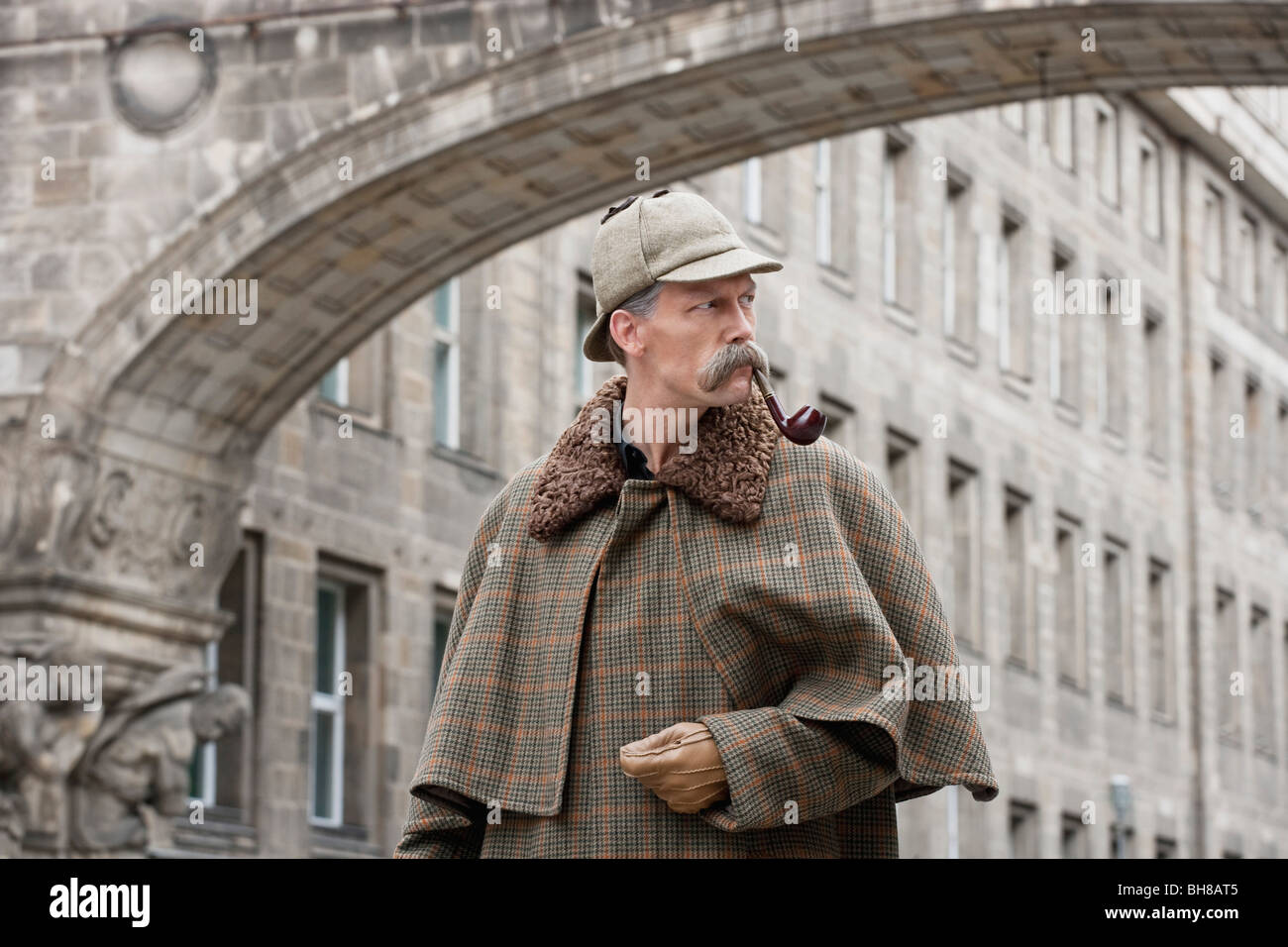 Un homme habillé comme Sherlock Holmes debout sous un bâtiment arch looking away Banque D'Images