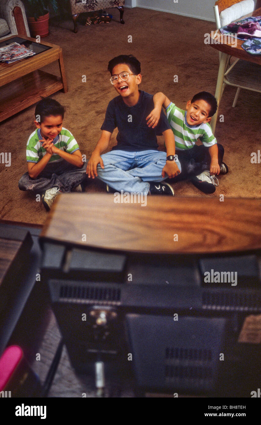 Trois garçons, deux Hispaniques, un Korean-American, regarder la télévision et rire Banque D'Images