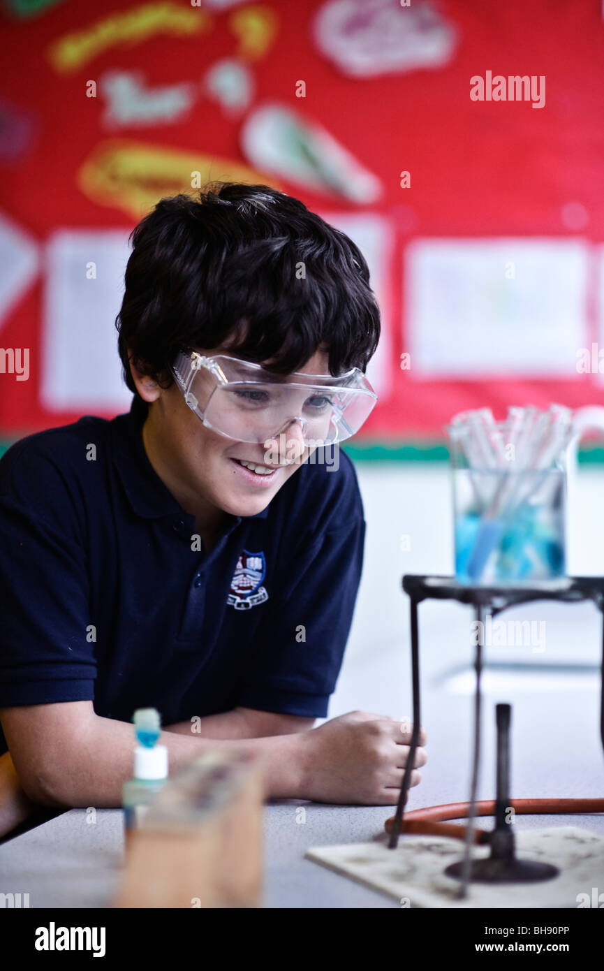 Jeune adolescent à l'école classe de sciences , au Royaume-Uni, portant des lunettes, regarder experiment Banque D'Images