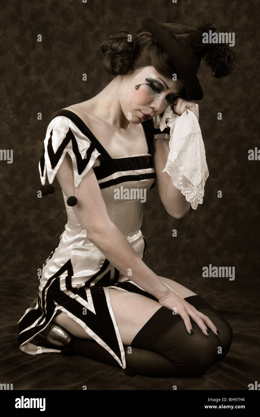 Jeune femme habillée d'une tenue de clown noir et blanc et chapeau noir, pleurer avec un mouchoir. Banque D'Images