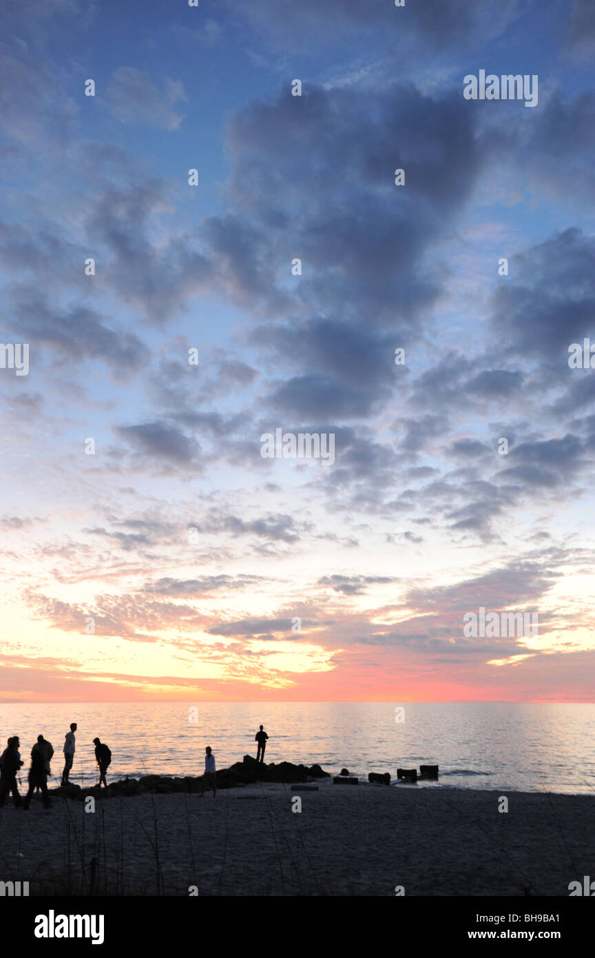 Un groupe de personnes silhouetté contre un spectaculaire coucher de soleil sur la plage de Naples Naples Florida USA Banque D'Images