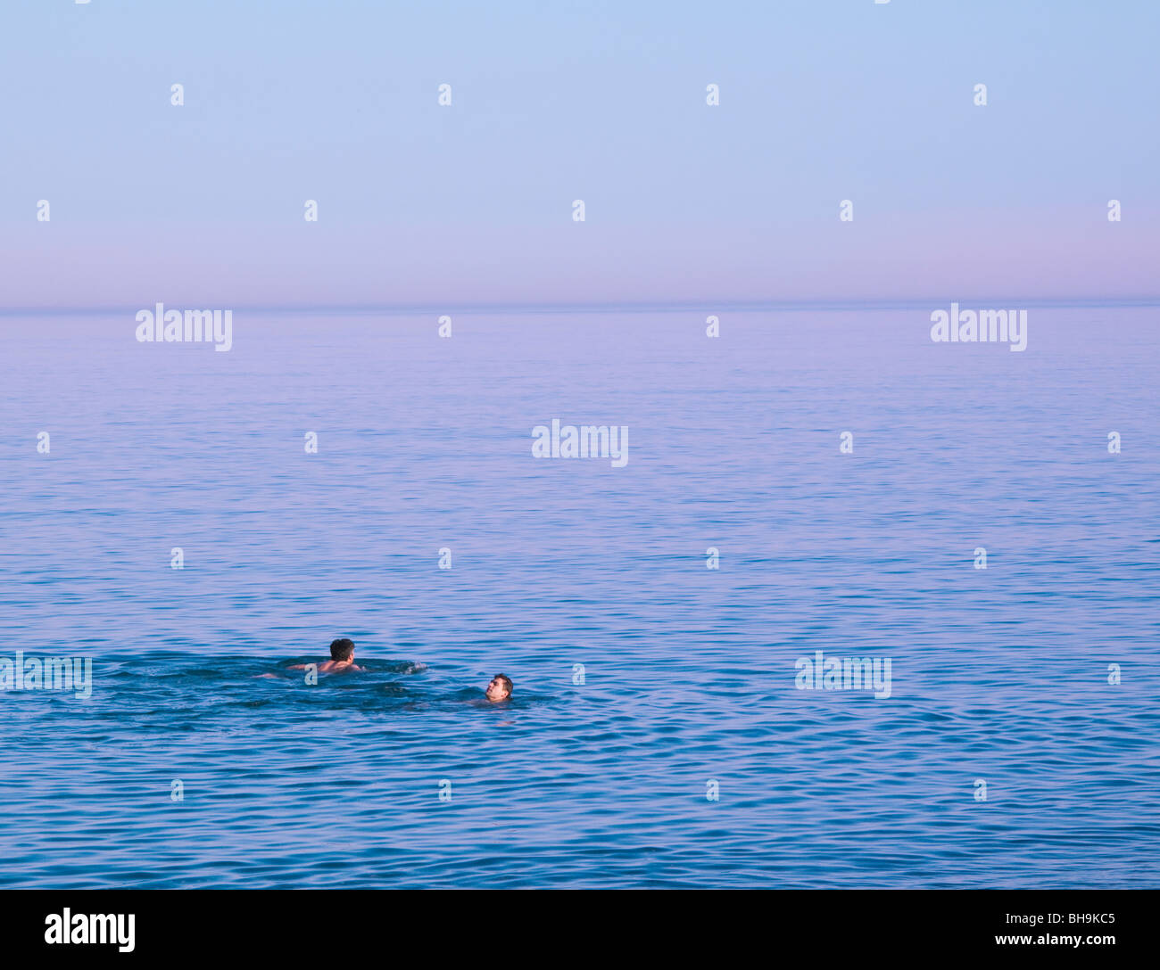 Deux nageurs natation en mer calme au crépuscule Banque D'Images