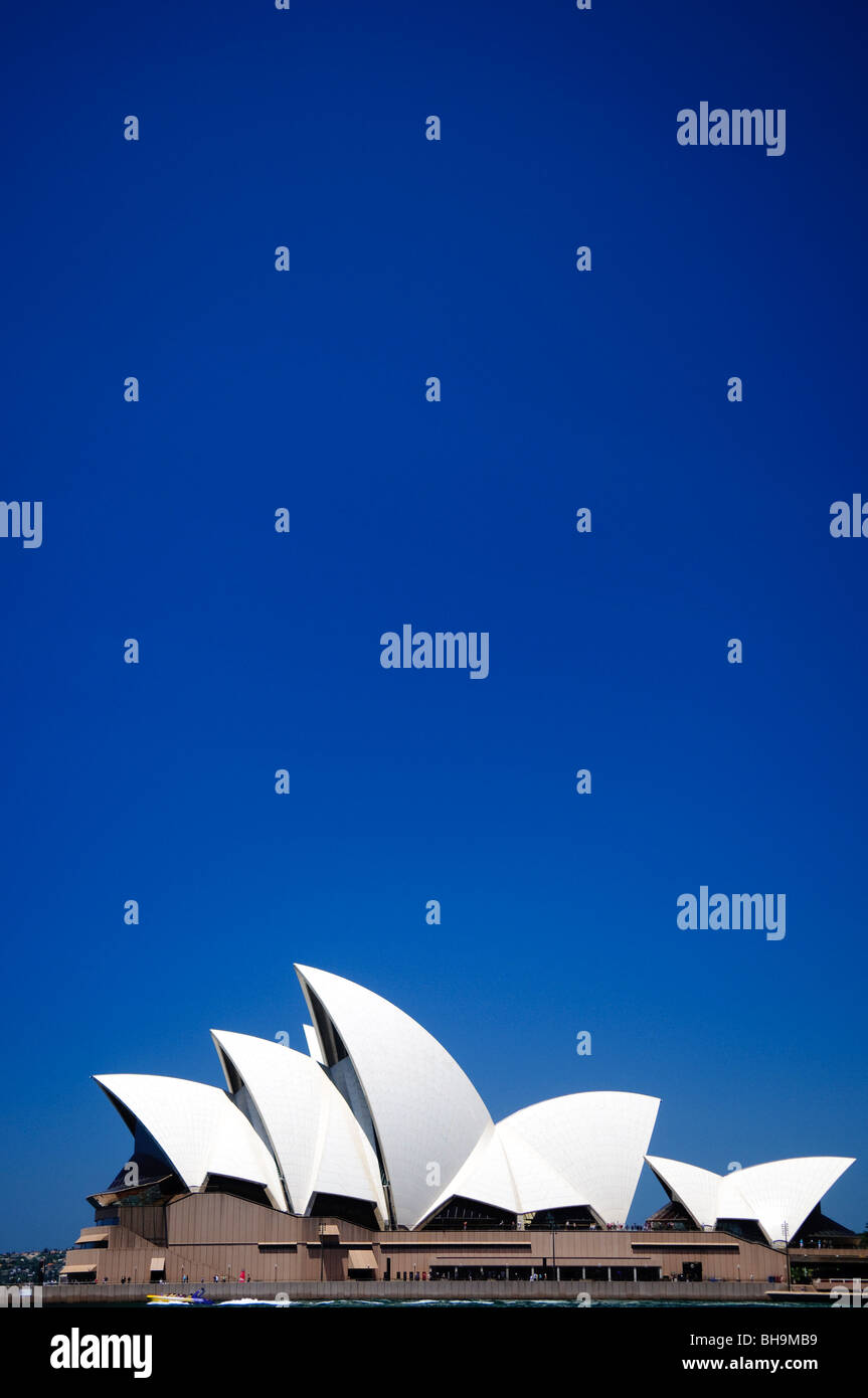 Sydney Opera House Sydney Australie // SYDNEY, Australie — L'Opéra de Sydney se dresse sur Bennelong point sous un ciel bleu clair par une journée ensoleillée. Le centre des arts de la scène classé au patrimoine mondial de l'UNESCO, conçu par l'architecte danois Jørn Utzon, a été achevé en 1973 et est reconnu dans le monde entier pour ses coquilles en forme de voile distinctives. Le bâtiment se trouve bien en vue au bord du port de Sydney, constituant le monument architectural le plus reconnaissable d'Australie et un lieu culturel majeur accueillant plus de 1 500 spectacles chaque année. Banque D'Images