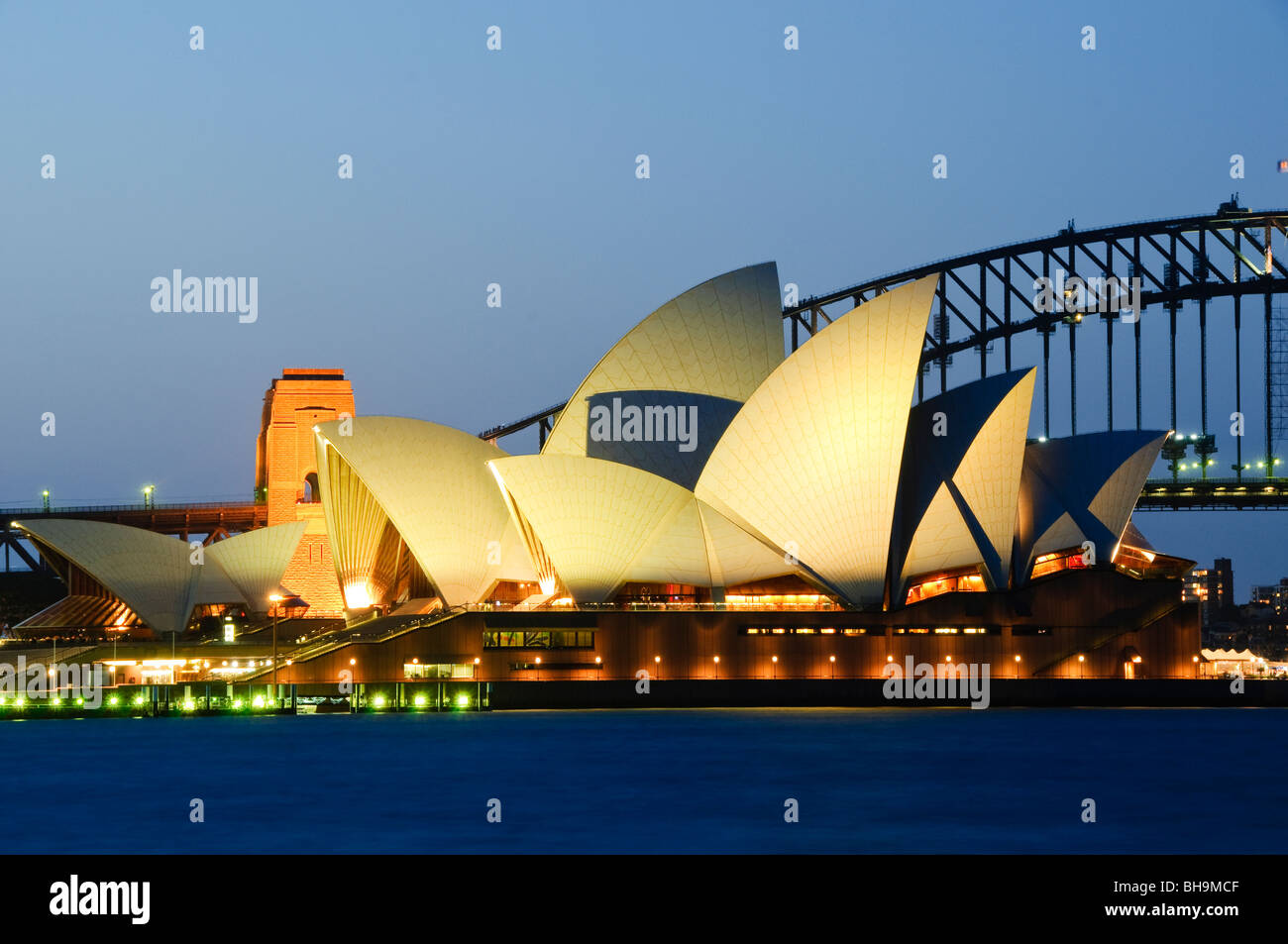 Opéra de Sydney Sydney Harbour Bridge Sydney Australie // SYDNEY, Australie — L'emblématique Opéra de Sydney est illuminé la nuit avec le Sydney Harbour Bridge visible en arrière-plan, vu depuis MRS Macquarie's point. Le site des arts de la scène classé au patrimoine mondial de l'UNESCO, conçu par l'architecte danois Jørn Utzon et achevé en 1973, présente ses coquilles en forme de voile caractéristiques qui sont devenues synonymes de la plus grande ville d'Australie. MRS Macquarie's point, situé dans les jardins botaniques royaux, offre l'un des points de vue les plus populaires pour photographier le monde de Sydney Banque D'Images