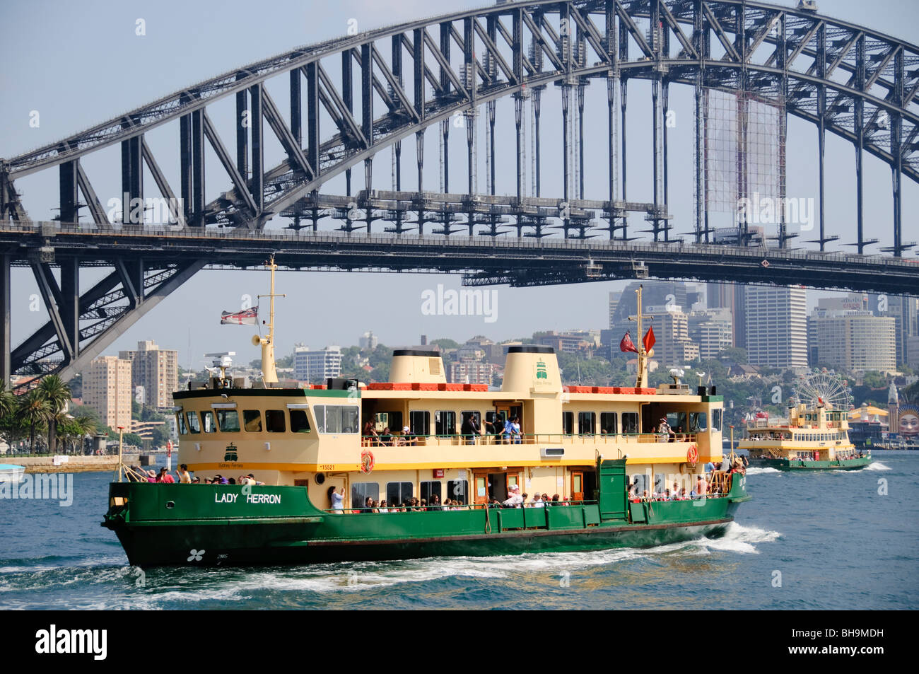 Sydney Harbour Bridge Sydney Ferry Sydney Australie // SYDNEY, Australie — Un ferry de Sydney, identifié comme « Lady Herron », navigue dans les eaux du port de Sydney avec l'emblématique Sydney Harbour Bridge en toile de fond. Le bateau est rempli de passagers qui apprécient le voyage pittoresque, tandis qu'un autre ferry, « Friendship », peut être vu plus loin dans le lointain avec pour toile de fond les gratte-ciel de la ville et Luna Park. Banque D'Images
