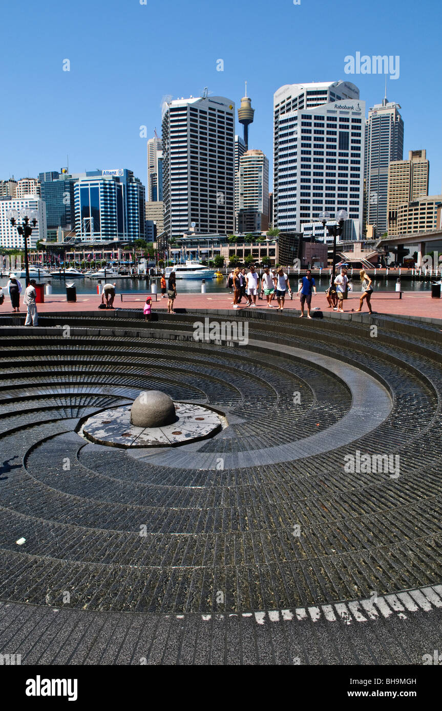 Darling Harbour Spiral Fountain Sydney Australie // SYDNEY, Australie — Une fontaine en forme de spirale est un élément important de Darling Harbour à Sydney. Le quartier animé du front de mer est animé par les gens, avec l'horizon moderne de la ville et l'emblématique Sydney Tower Eye visible en arrière-plan. Banque D'Images