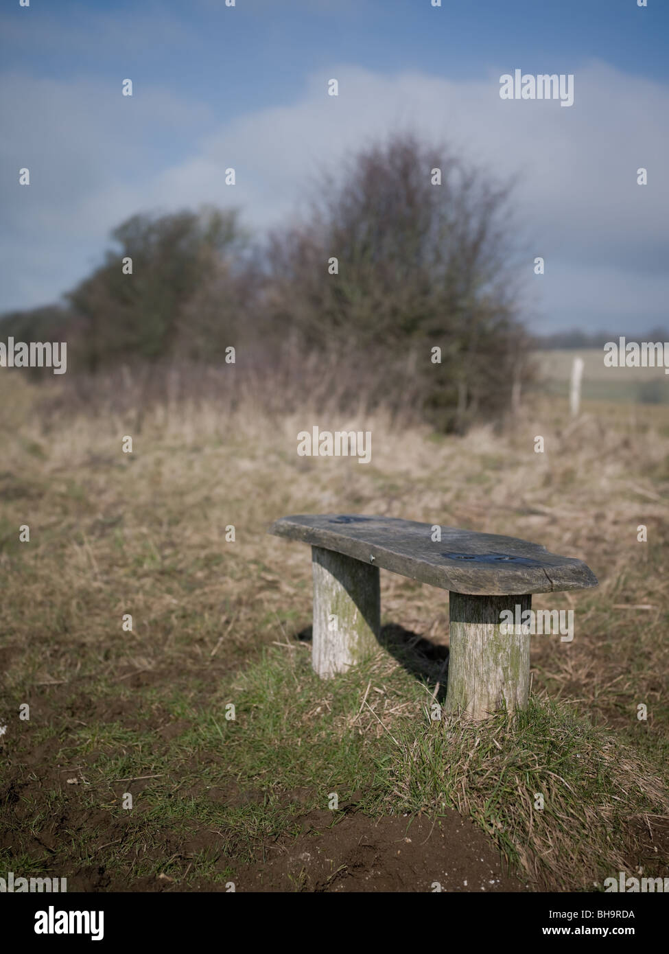 Un banc en bois, sur un chemin boueux par un champ dans la campagne. Banque D'Images