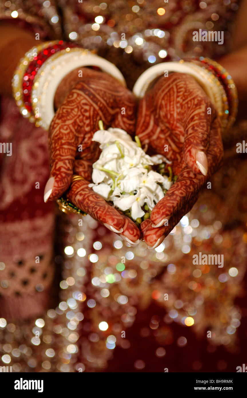 Conception henné sur une Indienne mariée, tenant des pétales de fleurs. Banque D'Images
