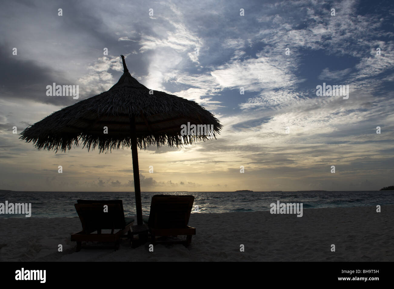 Silhouette de chaises de plage avec parasol au-dessus de la mer et du ciel. Banque D'Images