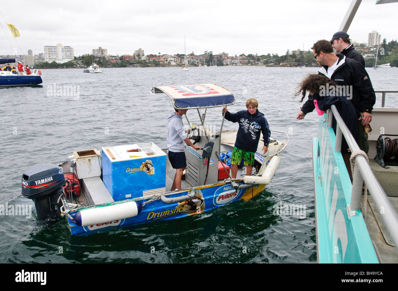Bateau de crème glacée Sydney Harbour Australia // SYDNEY, Australia — Youn entrepeneurs dans un petit canot vendant des glaces aux spectateurs au départ de la Rolex Sydney to Harbour Yacht Race 2009 dans le port de Sydney Banque D'Images