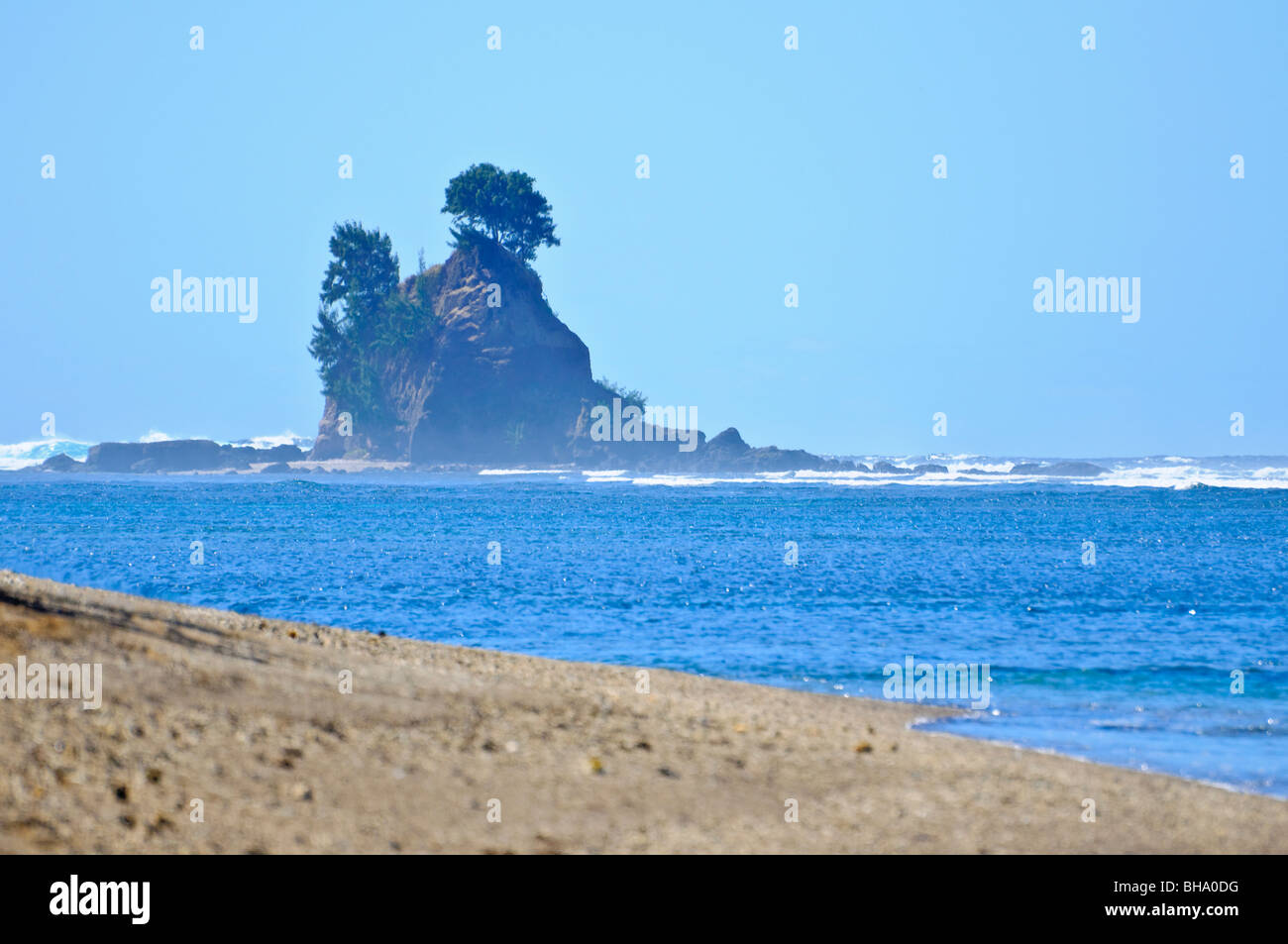 Rock formation au large depuis une plage tropicale non découvertes, avec les vagues de l'océan Banque D'Images
