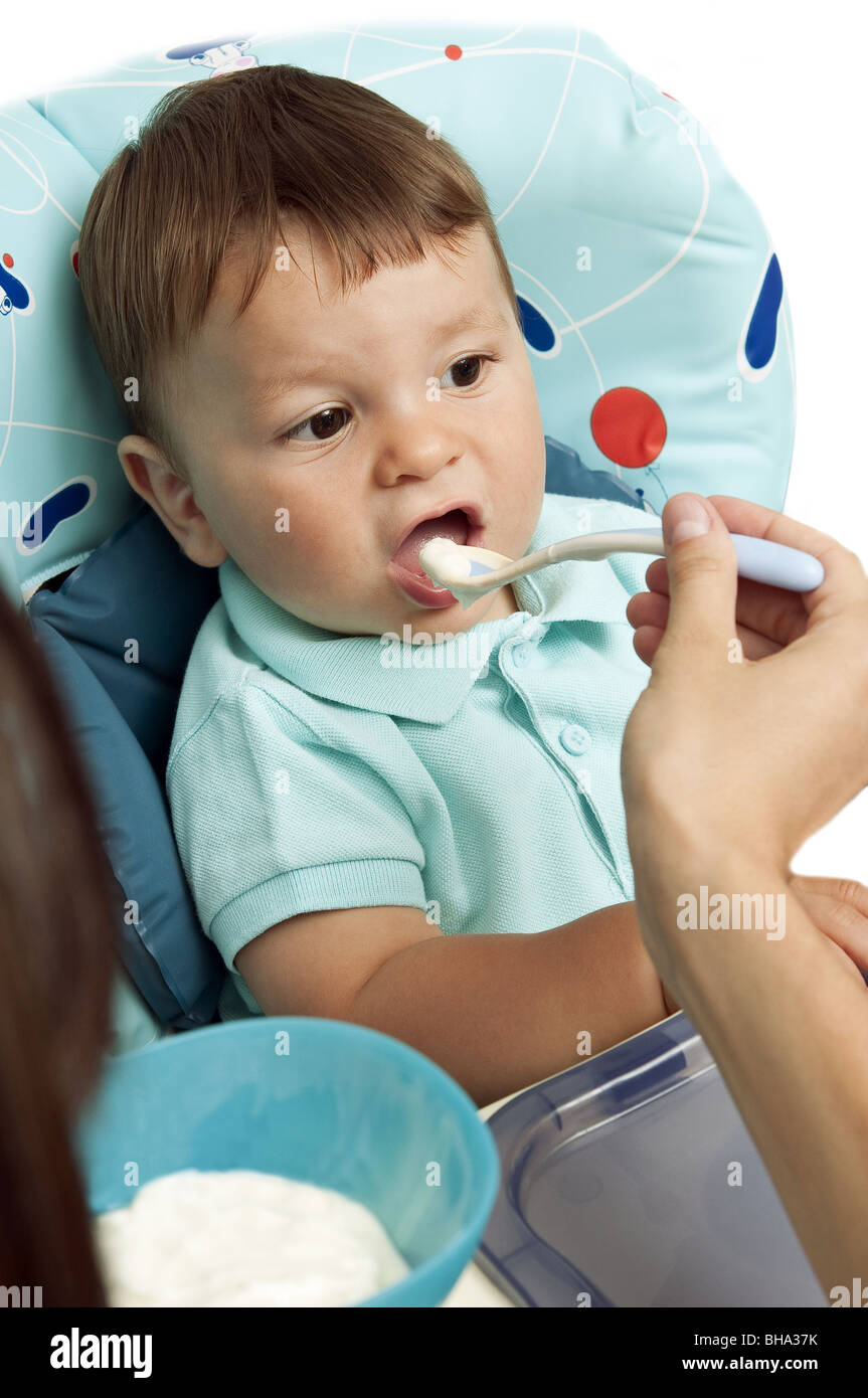 Jeune femme nourrir bébé garçon dans une chaise haute Banque D'Images