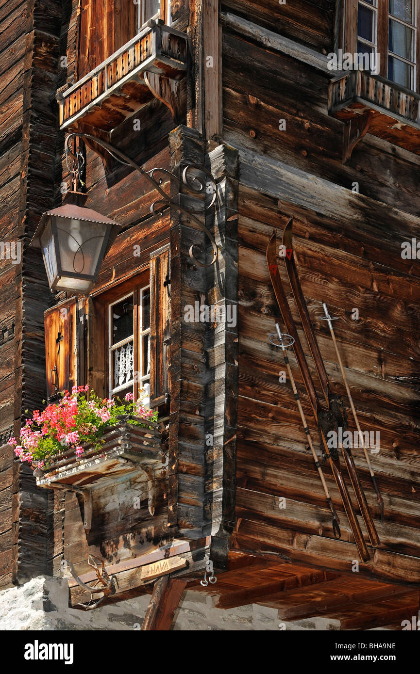 Avant de maison traditionnelle en bois décoré avec de vieux skis et de géraniums dans le village alpin de Grimentz, Valais, Suisse Banque D'Images