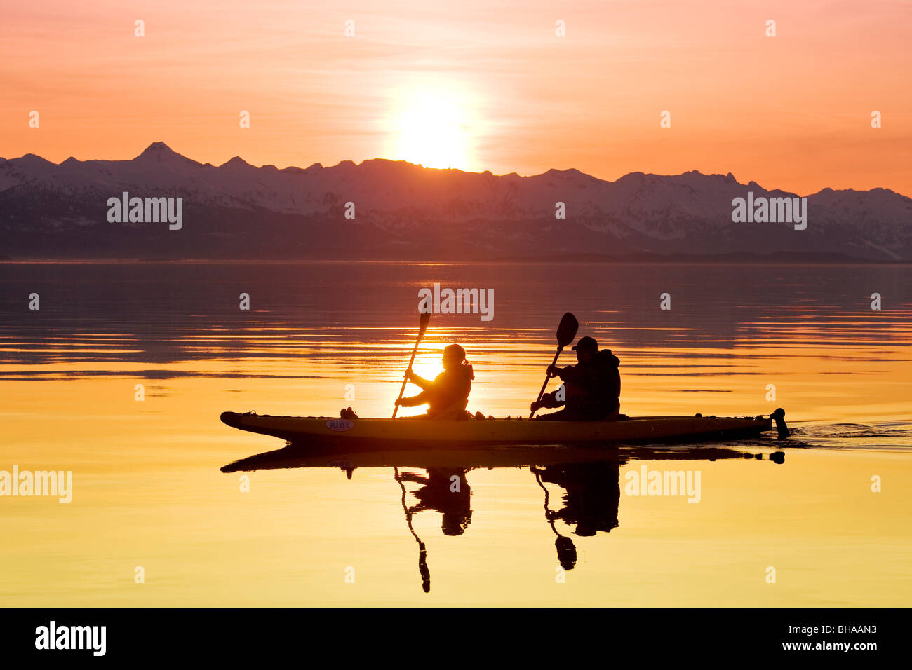 Pagaie de kayak les eaux calmes du Canal Lynn de l'Alaska au coucher du soleil avec les montagnes Chilkat dans l'arrière-plan Banque D'Images