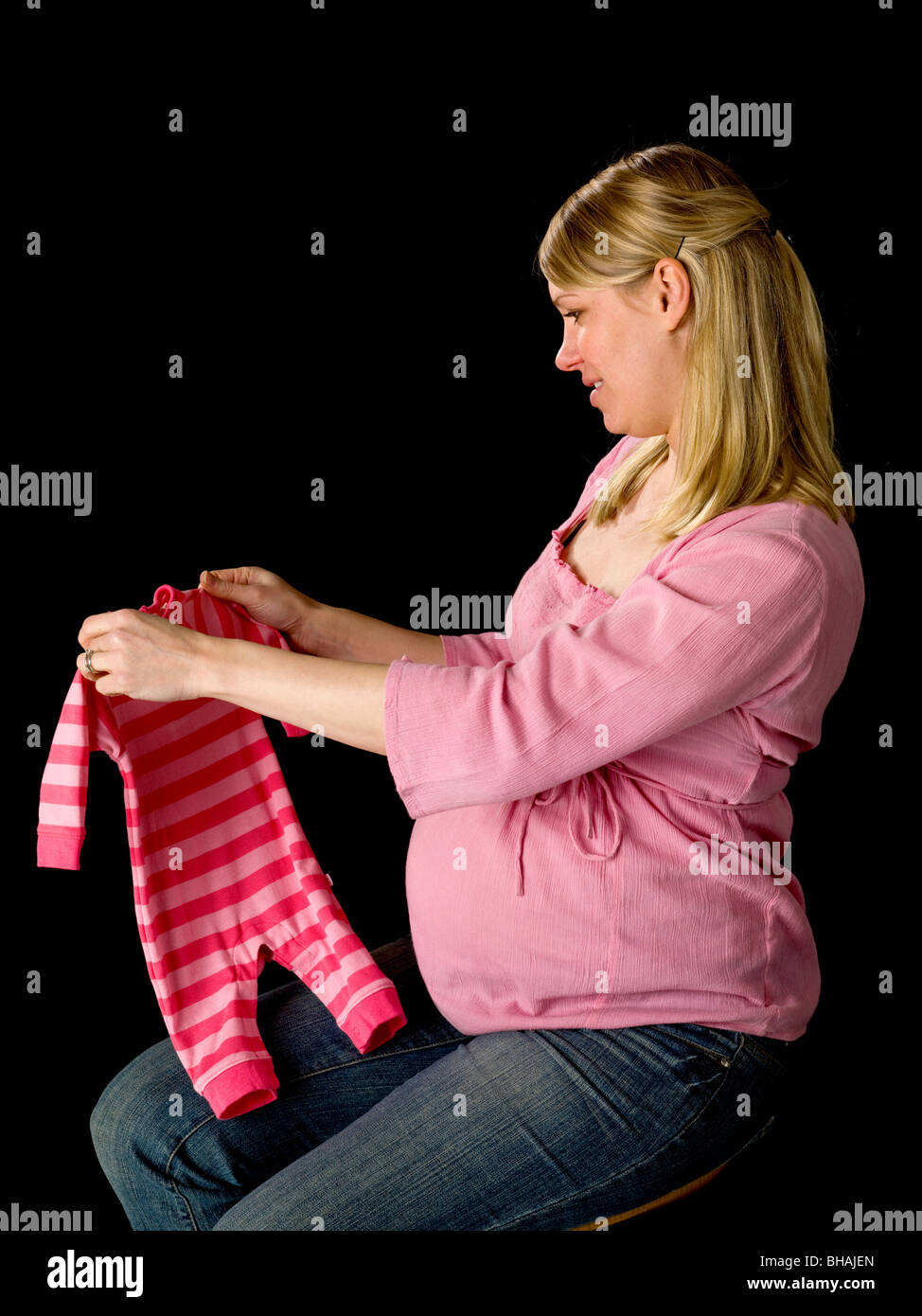 Pregnant Woman holding vêtements de bébé Banque D'Images