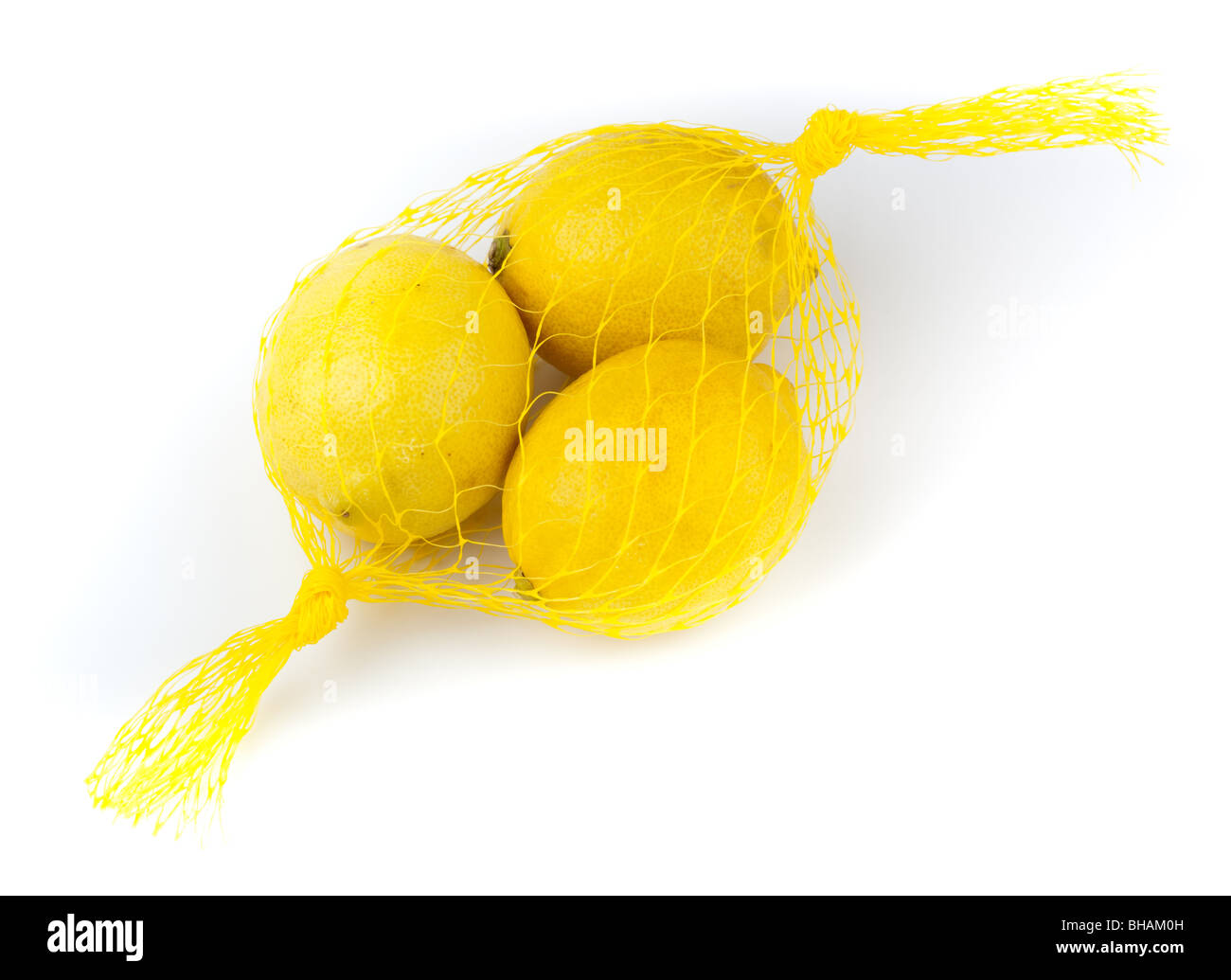 Trois citrons jaunes dans une chaîne-sac sur un fond blanc. Banque D'Images