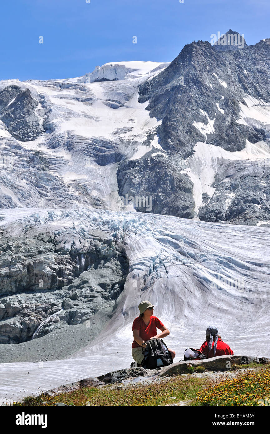 Les marcheurs / les randonneurs se reposant avec vue sur le glacier de Moiry en retraite, Alpes Pennines / Walliser Alpen, Valais / Wallis (Suisse) Banque D'Images