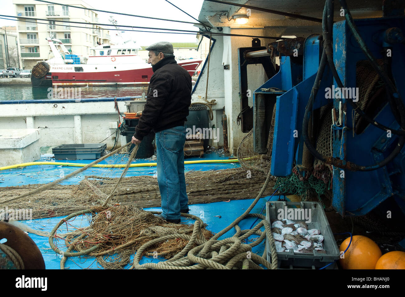 À bord d'un chalutier dans le port de pêche français de Sète en tant que net est enroulé et soirée Banque D'Images