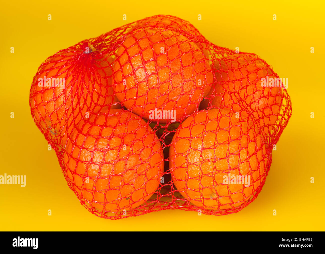 Les oranges dans une chaîne-sac sur un fond jaune. Banque D'Images