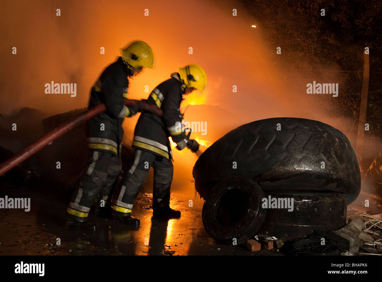 Les pompiers à combattre le feu la nuit dépôt de pneus Banque D'Images