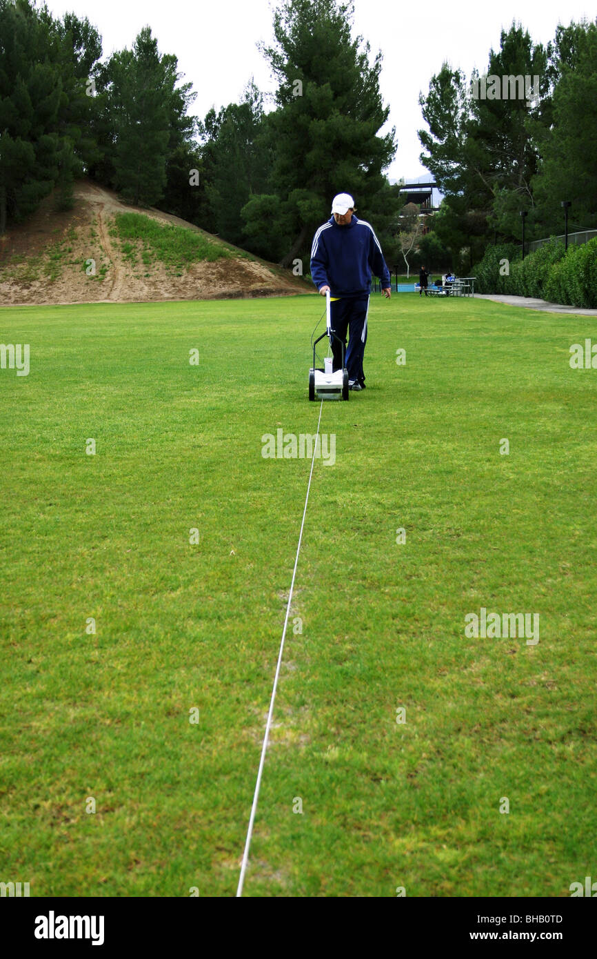 Footballeur français utilise une machine à revêtement line le champ de jeu avant un match. Banque D'Images