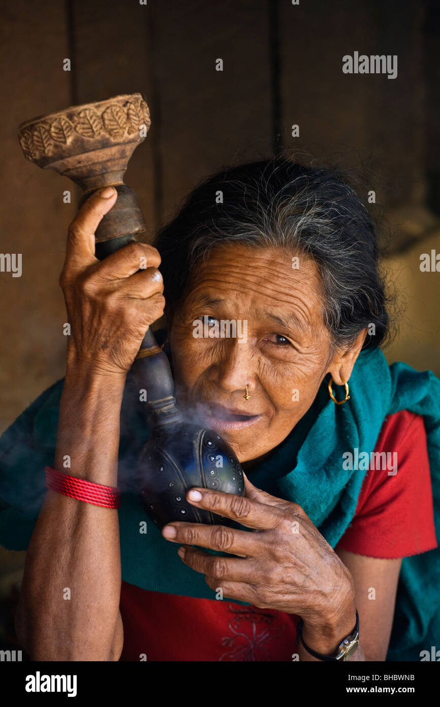 Un village népalais femme fume du tabac dans un tuyau à narguilé - AUTOUR DE MANASLU TREK, au Népal Banque D'Images