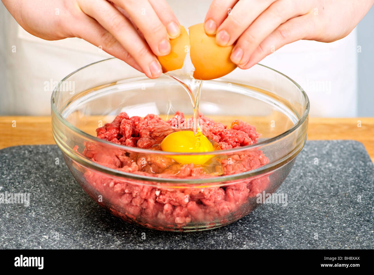 Fissuration Chef oeuf dans bol de boeuf haché Banque D'Images