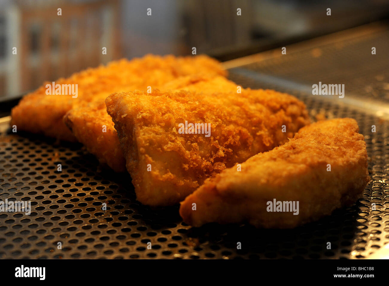 Des portions de Cabillaud frit dans une pâte dans l'armoire chaude dans un poisson et chip shop Banque D'Images