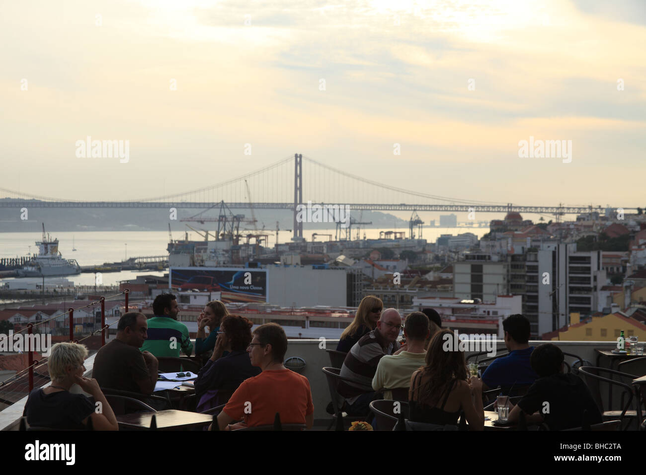 Les personnes ayant un verre dans une restaurant avec terrasse donnant sur le fleuve Tage et le 25 avril bridge Banque D'Images