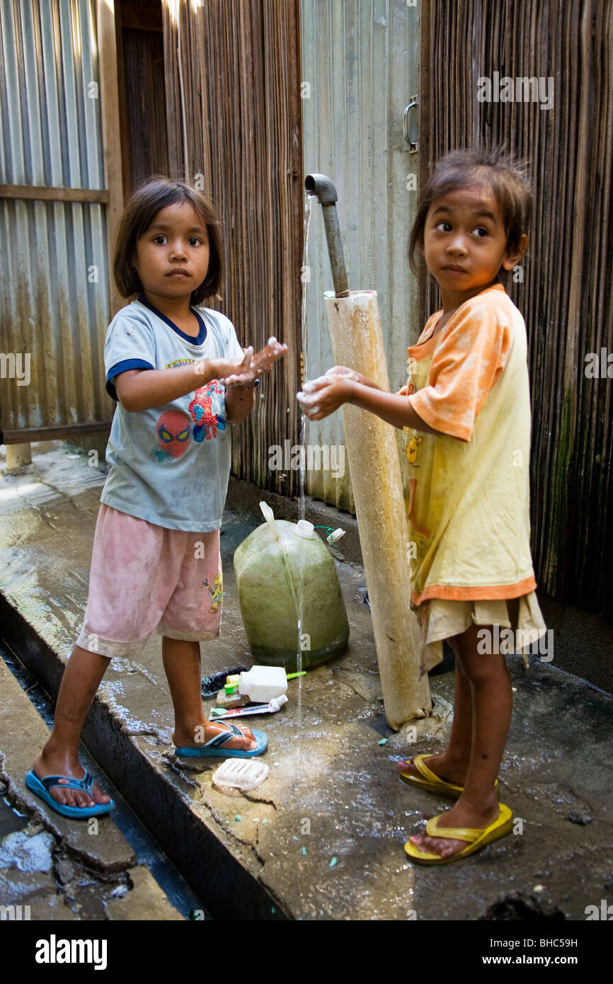 Les filles se laver à Dili le camp de personnes déplacées de l'hôpital où l'eau des toilettes et installé par Oxfam au Timor oriental Banque D'Images