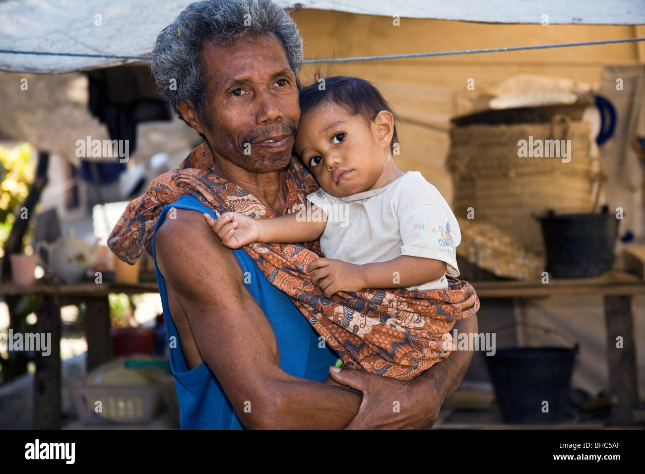 Soins Grand-père menuisier s'occupe de ses petits-enfants au camp de déplacés de sans-abri à Dili au Timor oriental Banque D'Images