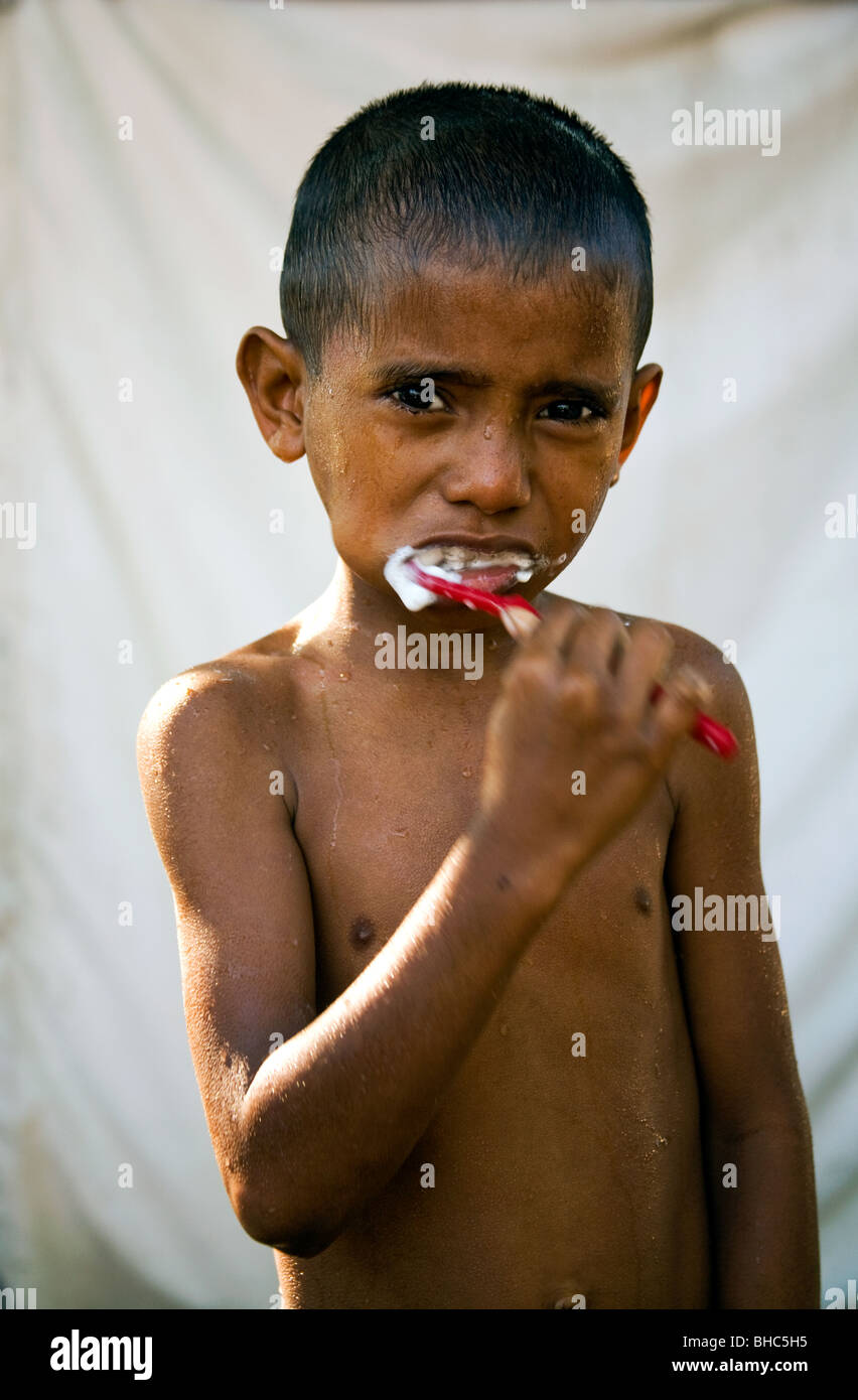 Garçon nettoie ses dents avec une brosse à dents pour la première fois fourni par le plan d'assainissement de l'eau au camp de personnes déplacées à Dili au Timor oriental Banque D'Images