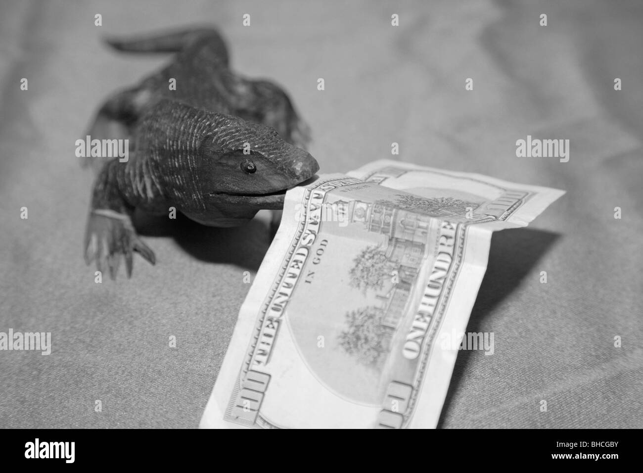 Lézard dragon de Komodo en bois sculpture souvenir nous mordre 100 Monnaie dollar bank note dans sa bouche Banque D'Images