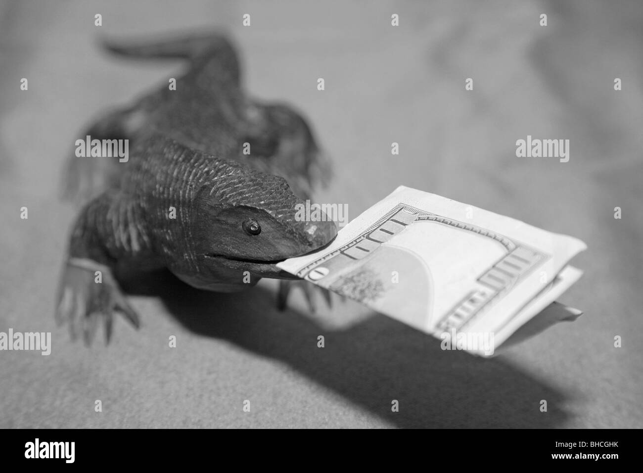 Lézard dragon de Komodo en bois sculpture souvenir nous mordre 100 Monnaie dollar bank note dans sa bouche Banque D'Images