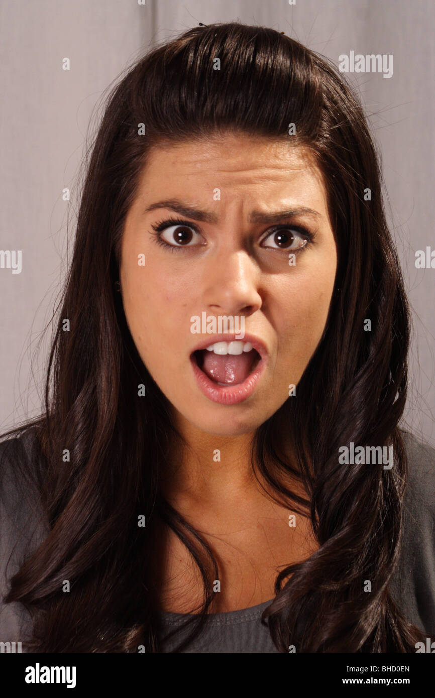 Jolie femme avec la bouche ouverte et l'expression choquée à la caméra en Banque D'Images