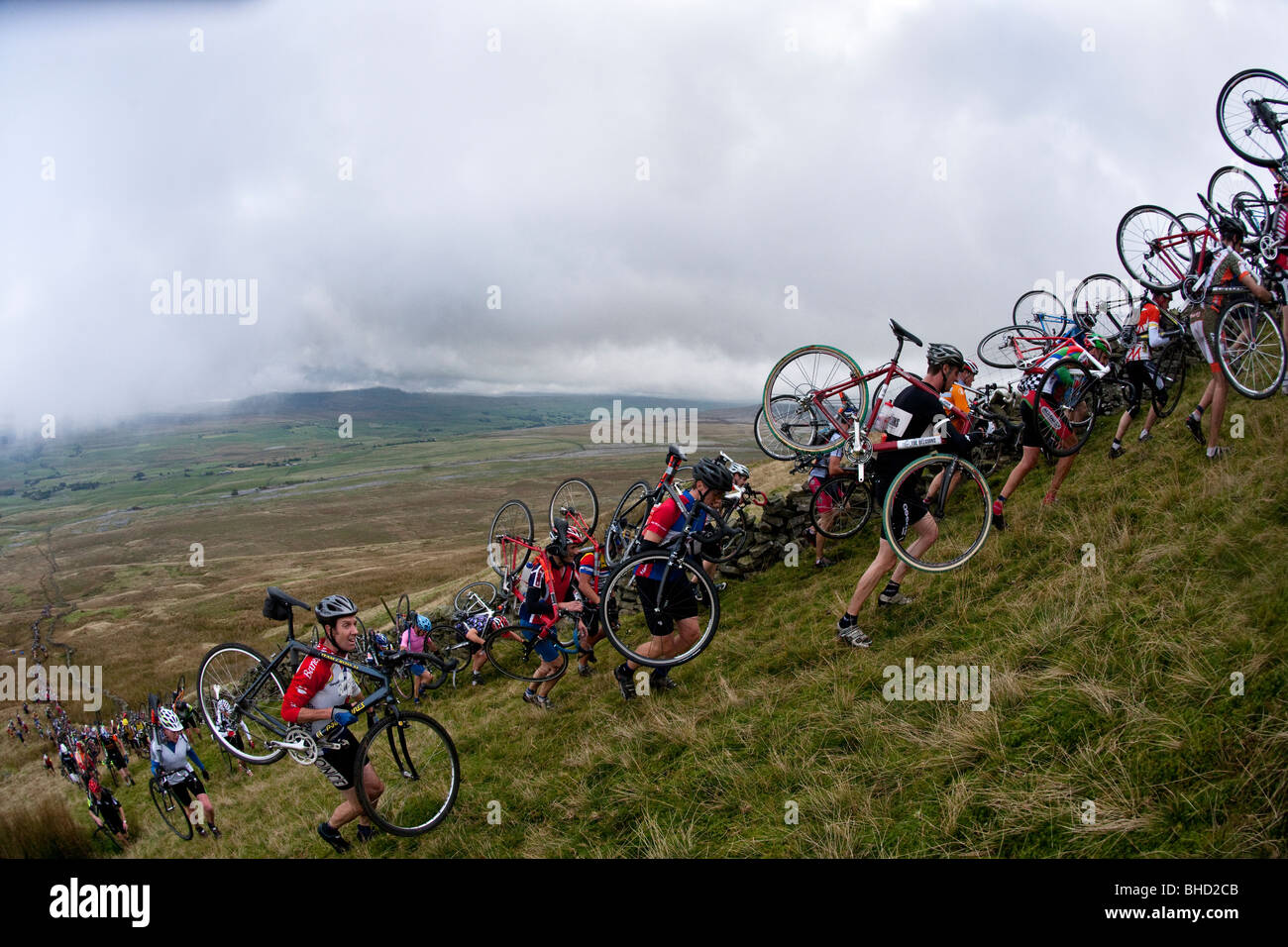 Foule de cyclistes portent leur vélo en montagne pendant les trois sommets Cyclo-Cross dans Yorkshire, Royaume-Uni Banque D'Images