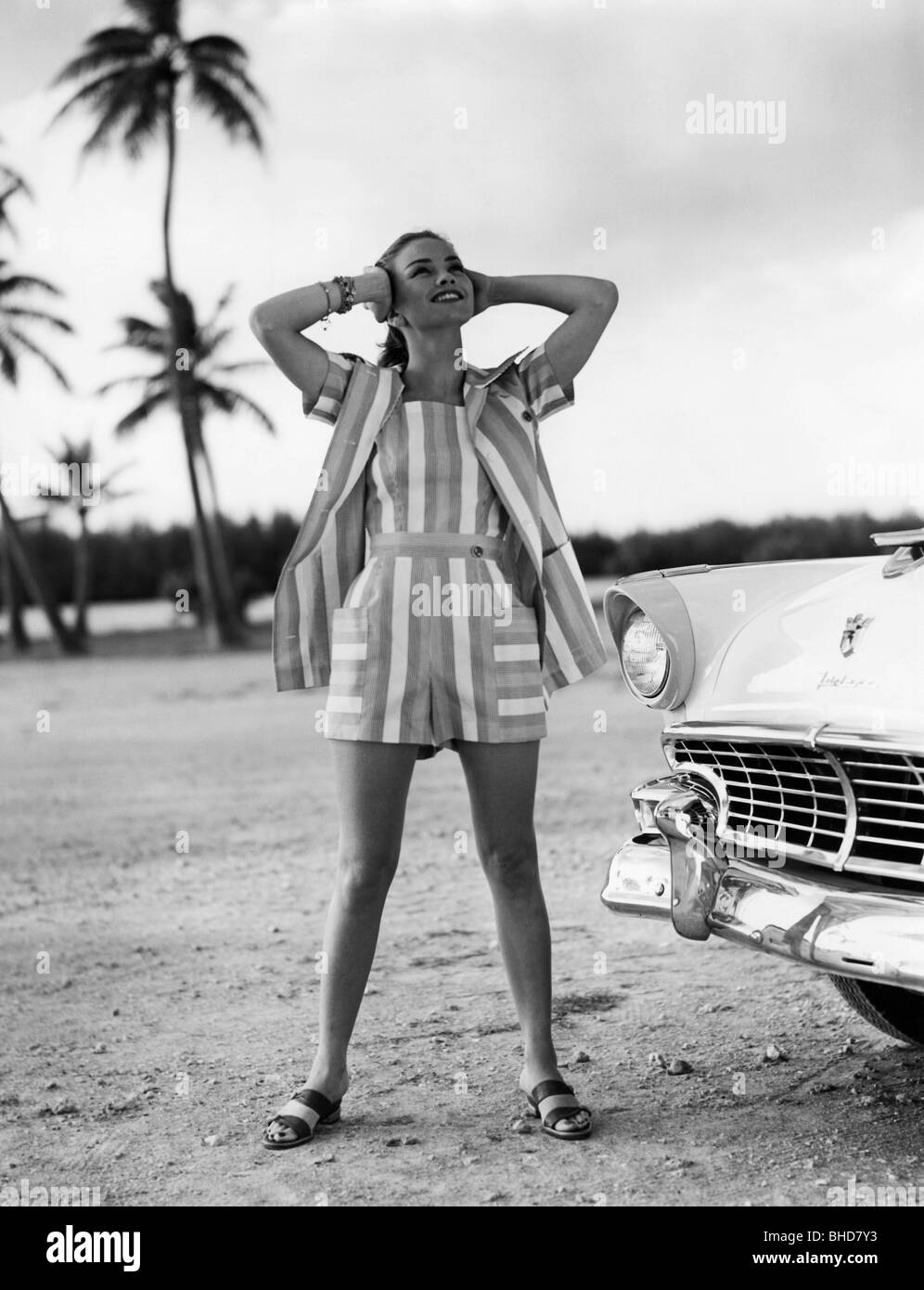 mode, jeune femme en robe d'été rayée, posant à côté d'une voiture, pleine longueur, années 1950, , Banque D'Images