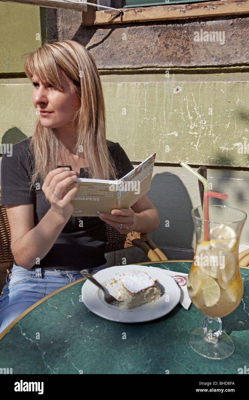 Une fille blonde la lecture d'un livre et d'avoir un strudel dans le château de Buda pâtisserie Ruszwurm Banque D'Images