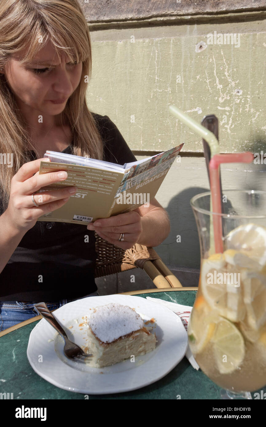 Une fille blonde la lecture d'un livre et d'avoir un strudel dans Ruszwurm traditionnels dans le château de Buda Banque D'Images